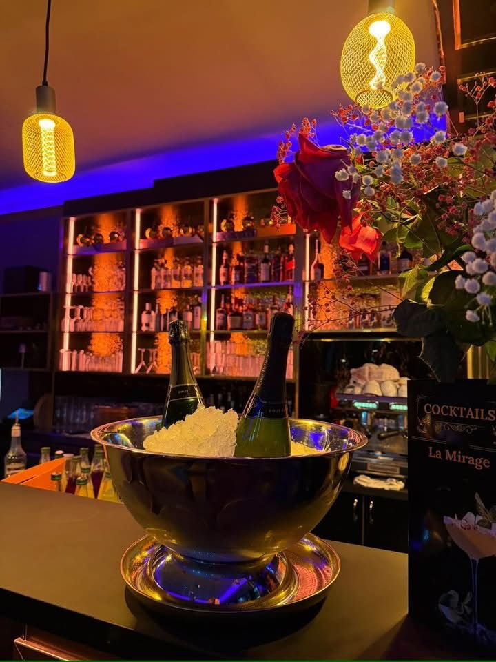 Zwei Sektflaschen stehen in einer silbernen Schale mit Eis auf einer stilvollen Bar