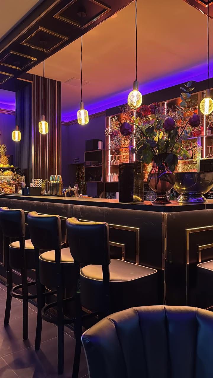 Edle Bar mit goldenen Akzenten violettem Stimmungslicht und üppigem Blumenschmuck